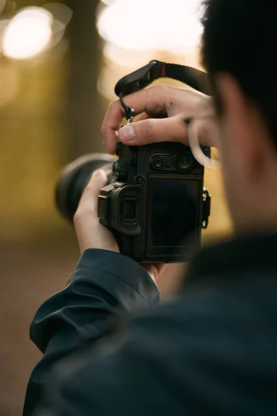 男は両手でミラーレスカメラを持ち 画面が見える 森の中で現代的なデジタルカメラで写真を撮る趣味の写真家の概念 — ストック写真