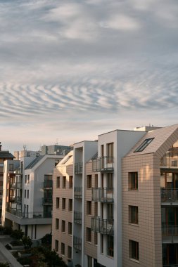 Gün batımında apartmanda. Akşamları apartman inşaatı var. Düşük seviyeli modern konut binasına güçlü güneş ışığı düşüyor.