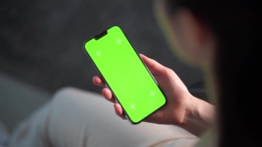 Akıllı telefonunu kapalı mekanda kullanan bir kadına yaklaş. Oturma odasında ekranı görünen bir kızın yeşil ekran modeli..