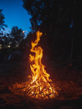 Kamp ateşi akşamı. Ateşin sıcaklığı soğuk ve ıslak ufukla çelişiyor..