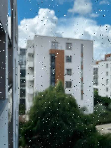 Window after rain. Rain droplets on window glass. Bokeh background of the Scandinavian style contemporary architecture.