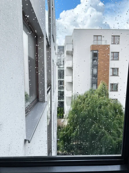 Window after rain. Rain droplets on window glass. Bokeh background of the Scandinavian style contemporary architecture.