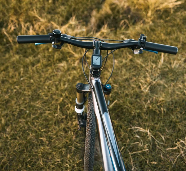 Bike handlebars. First-person view of mountain bicycle on the forest path. Riding a bike in a beautiful summer sunset nature landscape.