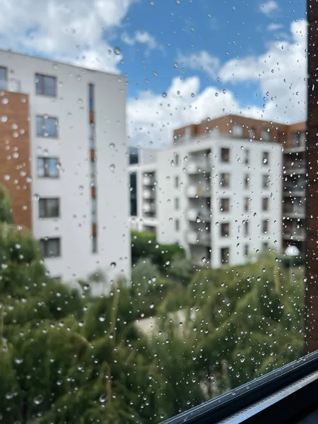 Window after rain. Rain droplets on window glass. Bokeh background of the Scandinavian style contemporary architecture.