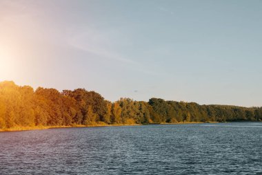 Beautiful summer sunset nature landscape. Tranquil evening scene with warm sunlight. Calm lake and green hills at sunset. Fishing time.