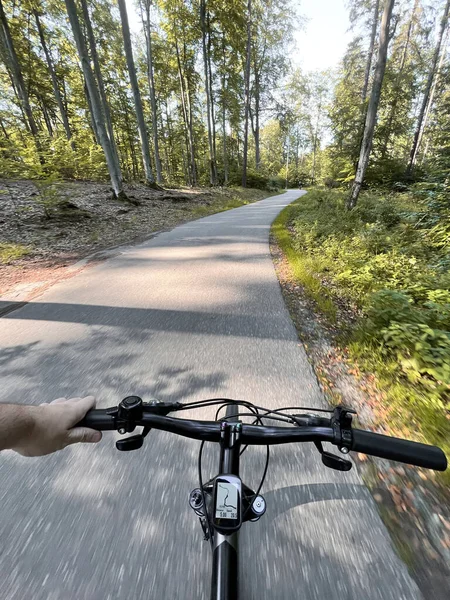 Close up of bicycle handle bar. First-person view of bicycle riding. Man riding a bike. Holding bike handlebar with one hand. Summertime outdoor leisure sport activity.
