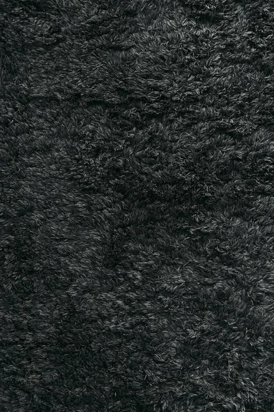 Black carpet on the floor. Long pile carpet for indoor use. Dark rug synthetic wool material.