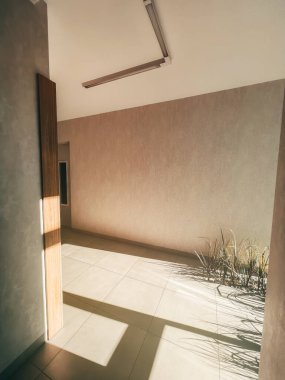 Vertical photo of long house corridor with a wooden door to flats. Indoor concept of a contemporary passage.