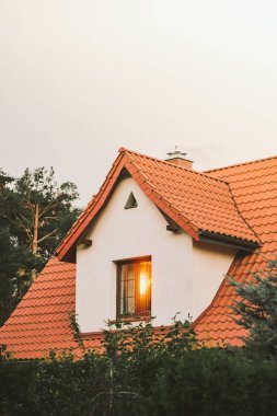 Akşam gökyüzüne karşı aile kulübesi. Bir evin detaylarını, pencerelerini, çatısını ve cephesini kapat.