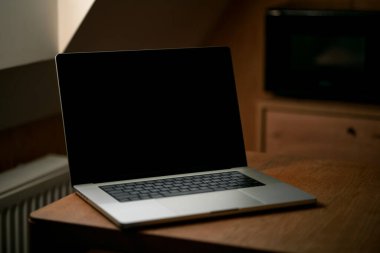 Evde boş ekranı olan bir masada dizüstü bilgisayar. Evde çalışma kavramı.