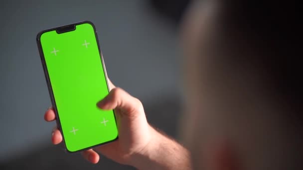 男の手は垂直画面が見えるスマートフォンを持っています 携帯電話を持っている男の手キーと追跡のための緑の画面で — ストック動画