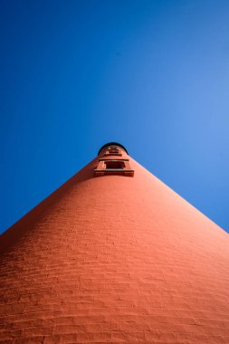 Açık mavi gökyüzü ve kopya için negatif alanı olan uzun bir deniz fenerine bakıyorum.