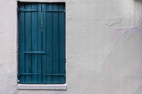 Painted blue wooden shutters and white stucco wall with negative space for copy