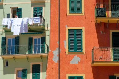 Camogli, İtalya - 10 Haziran 2022: Kadın Akdeniz 'deki Camogli köyünde kurutmak için temiz çamaşırlarını asıyor.