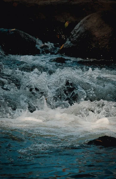 乱流の川の岩に囲まれた濃い青と泡の水 — ストック写真
