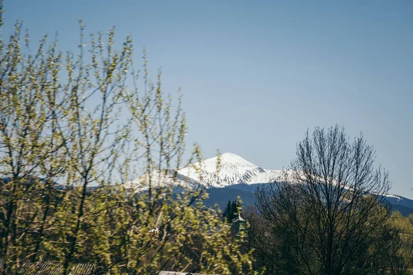 Montanha coberta de neve no horizonte, e aldeias de montanha — Fotografia de Stock