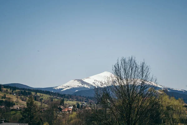Sněhem pokrytá hora na obzoru a horské vesnice — Stock fotografie