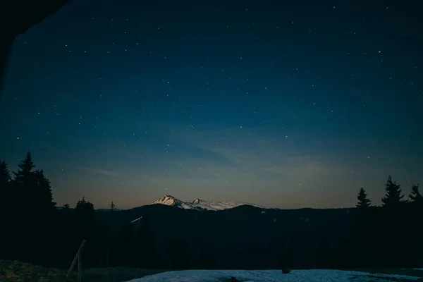 Prado nevado, montañas nevadas y estrellas en el fondo — Foto de Stock