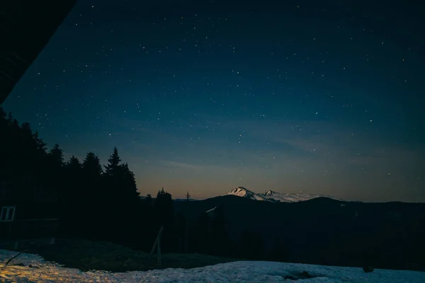 Prado nevado, montañas nevadas y estrellas en el fondo — Foto de Stock