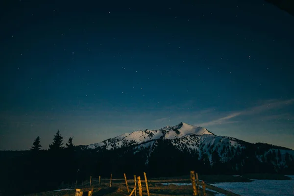 Prado nevado, montañas nevadas y estrellas en el fondo — Foto de Stock