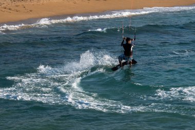 Nahariya, İsrail - 5 Kasım 2021 Galei Galil Plajı. Güneşli bir havada bir adam uçurtma uçuruyor. Yakın plan.