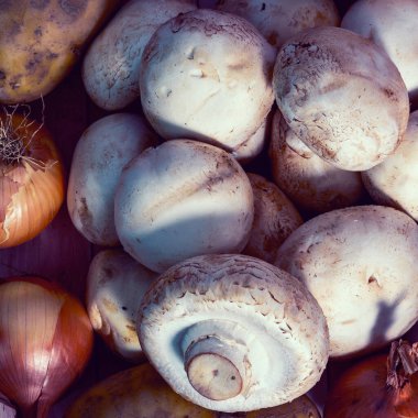 Taze sebzeler ve mantarlar bir tuğla duvarın arka planına yakın plan uzanır.
