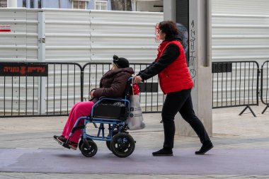Netanya, İsrail - 7 Şubat 2022: Yaşlı büyükanne ve torunu bahar doğasında tekerlekli sandalyede. Yakın plan..