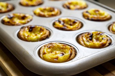 Yumurtalı tart, geleneksel Portekiz tatlısı, pastel de nata. Taze pişmiş. Fırından yeni çıkmış bir çarşaf uzanıyor..