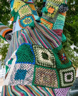 Ağaç gövdesi bombalamasına renkli örgü örülmüş. Sıcaklık, koruma ve dekorasyon için yamalı örgü örülmüş ağaç. Yüksek çözünürlük