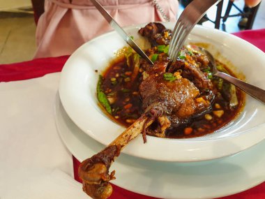 Baharatlı sosta kızartılmış ördek budu bir çatal ve bıçakla yenir. Yakın plan..