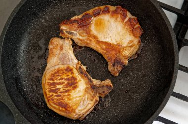 Kızarmış domuz bifteği ve tavada kemik var. Yakın plan..