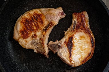Kızarmış domuz bifteği ve tavada kemik var. Yakın plan..