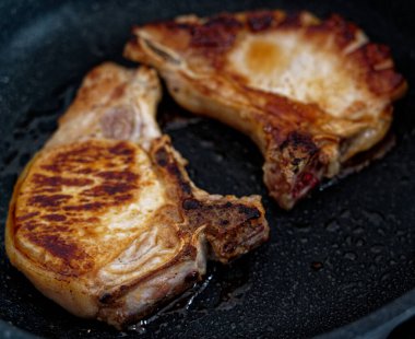 Kızarmış domuz bifteği ve tavada kemik var. Yakın plan..