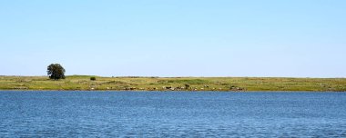 Golan Tepeleri 'ndeki Shabania Gölü' nün panoramik manzarası yeşil bir ovaya ve uzaktaki bir sıradağlara bakıyor. Yüksek çözünürlüklü.
