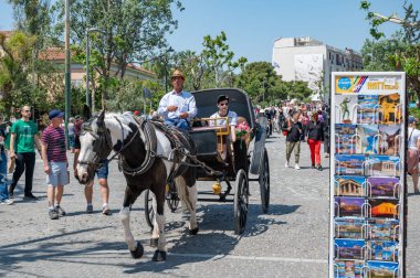 ATHENS, GREECE - MAY 14, 2022: The famous tourist area of Plaka under the Acropolis in Athens, Greece. Horse-drawn carriage ride.