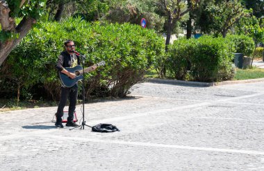 ATHENS, GREECE - MAY 14, 2022: A street musician with a wind musical instrument stands near the fence and plays the instrument in Athens.