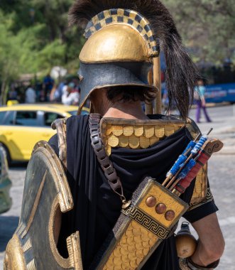 ATHENS, GREECE - MAY 14, 2022: the artist is dressed in a costume of an ancient Greek warrior for photographing in a park near the Acropolis. Sunny day.