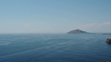 Panoramic video of the sea with a lonely mountain. Sailboats and motor boats float.