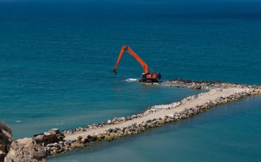 Kazıcı taşları denize taşır. Netanya, İsrail 'de sahili korumak için dalgakıran inşaatı. Endüstriyel yapı ekipmanı ve makineleri.