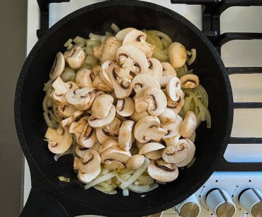 Beyaz şampiyon mantarları kızartma tavasında soğanla kızartılır. Yakın plan..