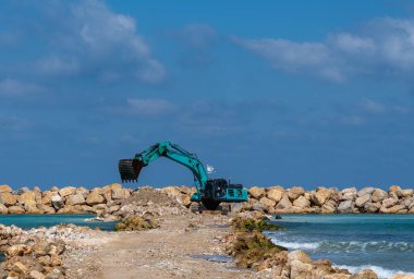 Kazıcı taşları denize taşır. Netanya, İsrail 'de sahili korumak için dalgakıran inşaatı. Endüstriyel yapı ekipmanı ve makineleri.