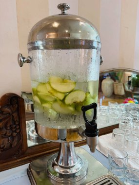 Otel lobisinde içinde soğuk içme suyu, meyve ve nane parçaları olan şeffaf bir tank var. Yakın plan..