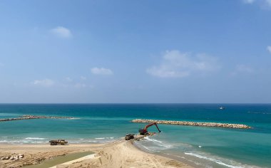 Bir kazıcı ve bir maden kamyonu taşları denize taşır. Netanya, İsrail 'de sahili korumak için dalgakıran inşaatı. Endüstriyel yapı ekipmanı ve makineleri.