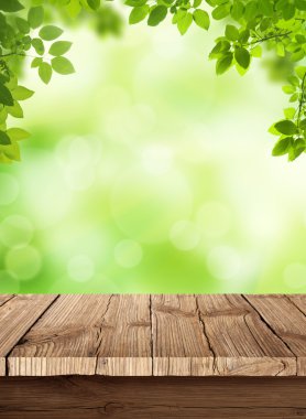 Fresh spring green bokeh background with wooden table for your products displays clipart
