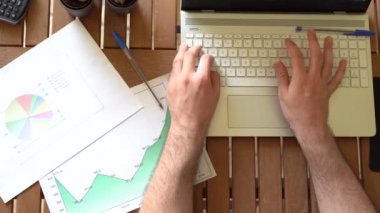 Genç bir adamın çalışma saatlerinde masa başında bilgisayarda daktilo yazışının en üst görüntüsü..