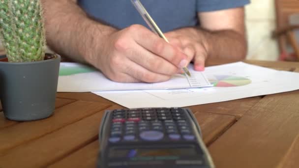 Jovem Não Reconhecido Analisando Gráficos Mesa Com Uma Calculadora Enquanto — Vídeo de Stock