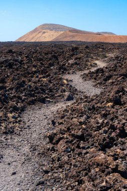 İspanya 'daki Kanarya Adaları, Lanzarote' deki eski lav volkanına giden yol. Volkanik manzara.