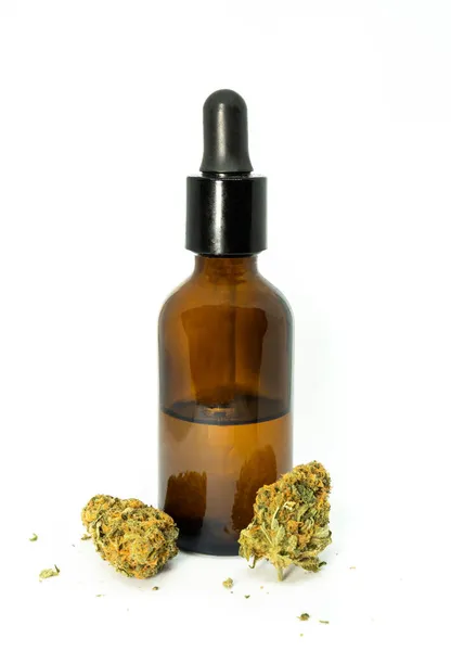 Bir şişe yağ, CBC ve marihuana tomurcukları. CBD, kenevirden elde edilen tıbbi kullanıma yönelik bir hazırlık.