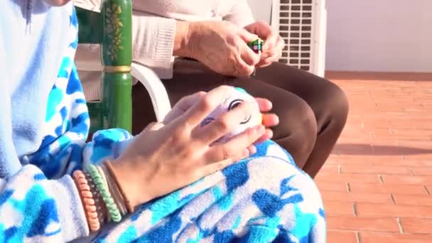作物の上から匿名の祖母と孫娘が晴れた日にベランダに座ってカラフルな教育用おもちゃで一緒に遊んでいます — ストック動画