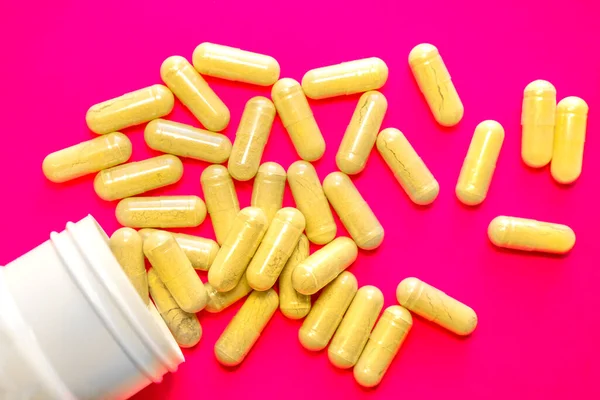분홍색 배경에 노란 알약이 담긴 병, 약국 컨셉 — 스톡 사진